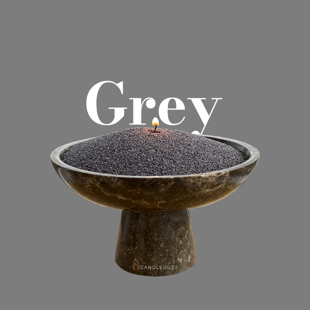 Lit candle burning in grey candle sand, unbound wax sold by weight